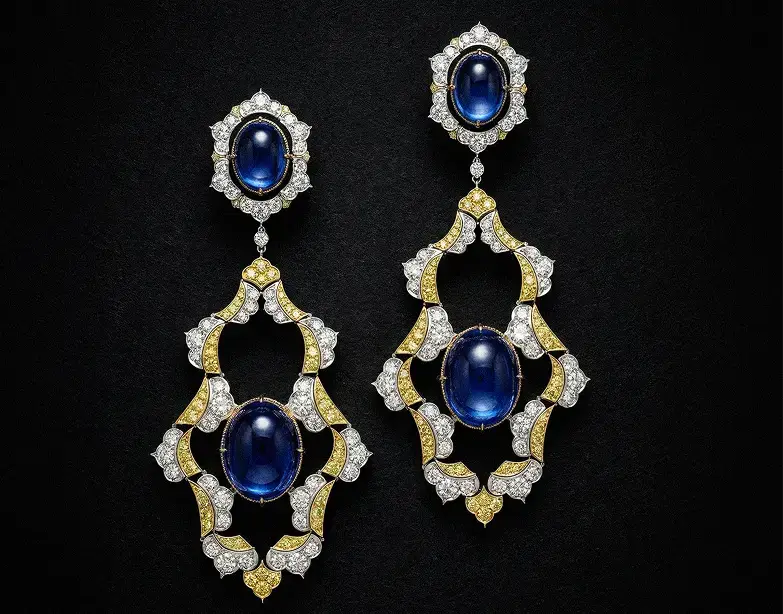 The earrings "The Sapphier Ascend" on display. They have the shape of golde feathers with no filling. In the center there is one big ova sapphire and it has an upper part that can be detached. This part is a hexagon encrsuted with gold and diamonds with another oval sapphire in the center